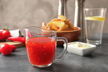Glass pitcher with chili sauce on kitchen table