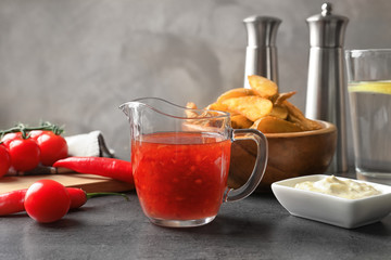 Glass pitcher with chili sauce on kitchen table