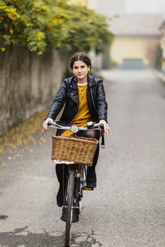 Young woman with modern outfir riding an old bicycle