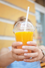 Woman holding plastic cup with juice outdoors
