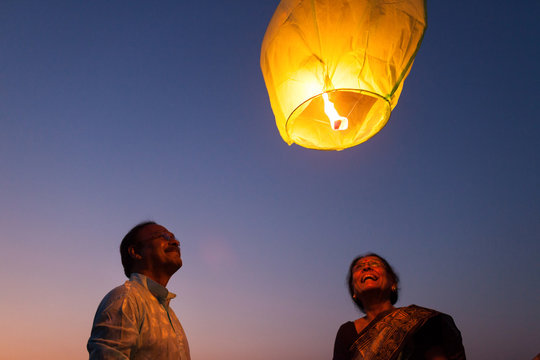 Senior couple releasing sky lantern to the sky at twilight