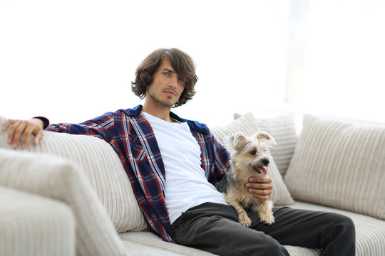 stylish guy sitting on the couch with his dog.