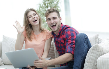 happy couple laughing ,sitting on the couch in front of the open laptop