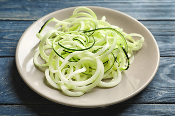 Plate with zucchini spaghetti on wooden background
