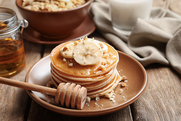 Plate with yummy banana pancakes on wooden table