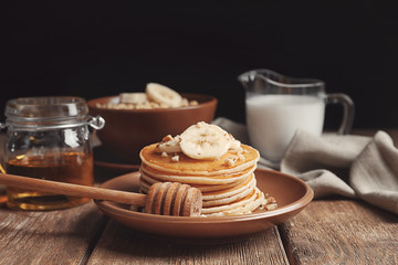 Plate with yummy banana pancakes on wooden table