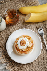 Plate with yummy banana pancakes on kitchen table
