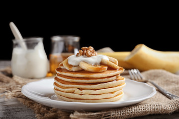 Plate with yummy banana pancakes on kitchen table