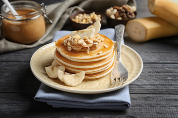 Plate with yummy banana pancakes on wooden table
