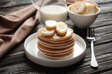 Plate with yummy banana pancakes on wooden table