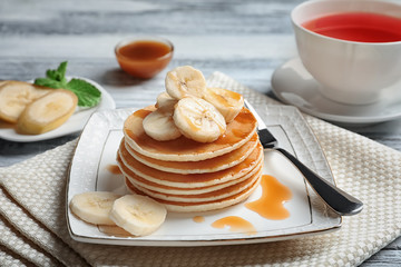 Plate with yummy banana pancakes on kitchen table