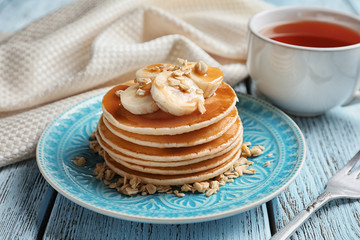 Plate with yummy banana pancakes on wooden table