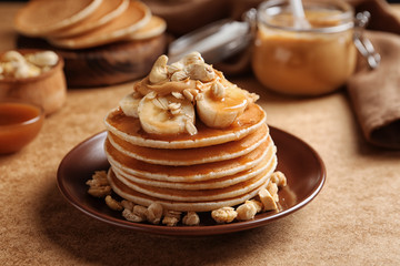Plate with yummy banana pancakes on kitchen table