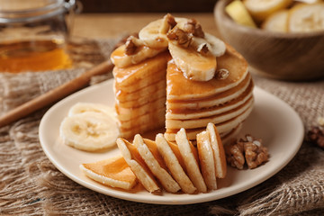 Fototapeta na wymiar Plate with yummy banana pancakes on kitchen table