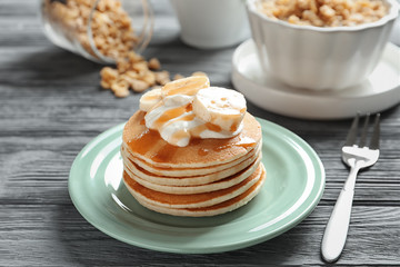 Plate with yummy banana pancakes on wooden table