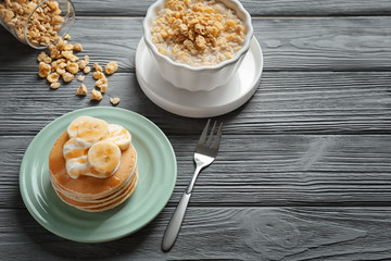Plate with yummy banana pancakes on wooden table