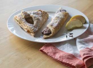sweet apple and nuts puff pastry cake with slices of apple cloves and napkin on wooden table