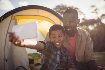 Father and son taking selfie with mobile phone in park