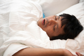 Fototapeta na wymiar Asian man is snoring in bed and his have sleep apnea, Health care concept.