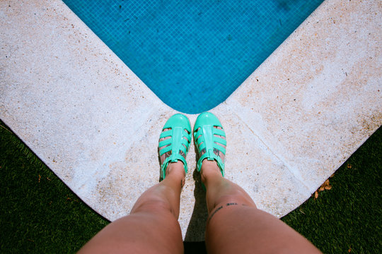 Woman's legs on the edge of the pool with sandals
