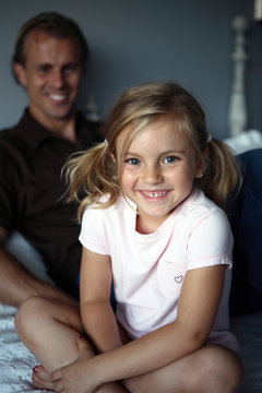 Daughter WIth Ponytails Smiling With Dad in Background