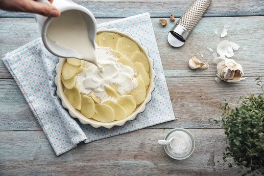 Food: Prearing gratinated potatos, pouring cream onto potatos