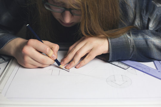 Long haired teenage boy drawing technical graphics...