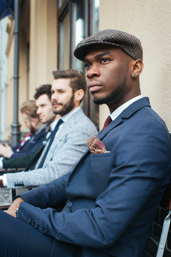 Outdoor Portrait of Handsome Young Black Man Sitting with Friends in Caf??_??