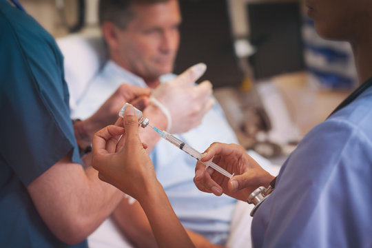 Hospital: Nurses Prepare To Administer Shot Of Medicine To Patient