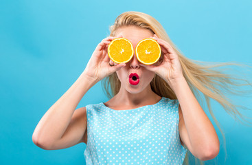 Happy young woman holding oranges on a solid background