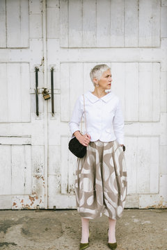 Fashionable Senior Woman Standing in Front of the White Door