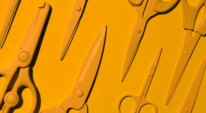 Yellow scissors on yellow background