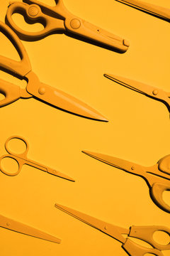 Yellow scissors on yellow background