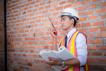 Asian engineer man with blueprints with brick wall background