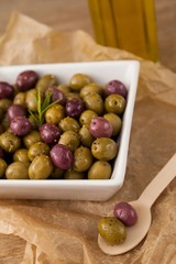 Close up of olives with rosemary served in bowl on paper