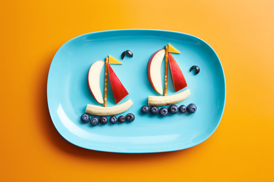 Blue plate with edible fruits and berries in form of boats