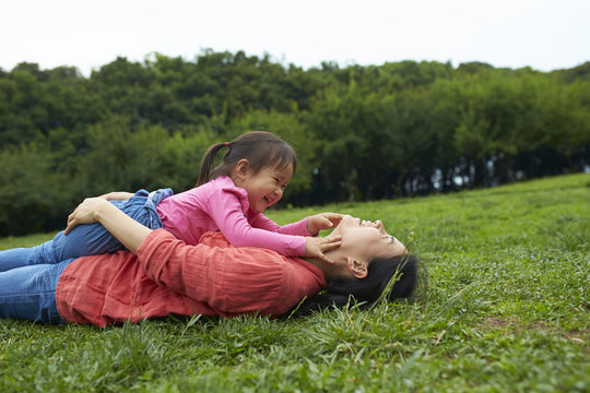happy little asian girl playing with her mother outdoor in the park