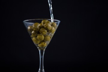 Martini pouring into glass with olives