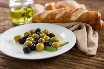 Marinated olives with olive oil and breakfast on wooden table
