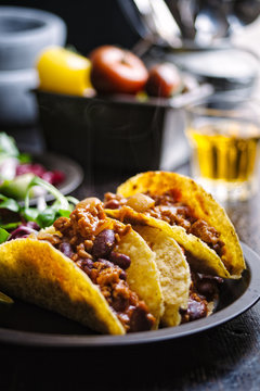 A plate of pork tacos and a beer in the background.