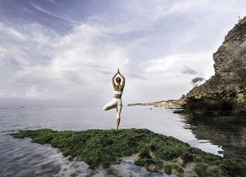 woman practicing yoga at sea shore
