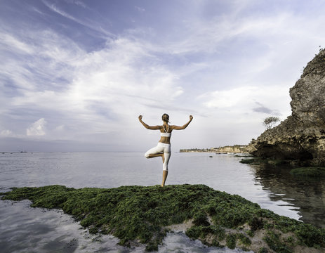 woman practicing yoga at sea shore