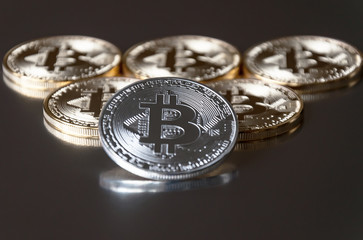 A few gold and silver coins bitcoin lie or stay on edge on a dark background. The concept of crypto currency