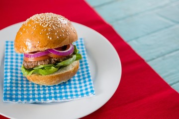 Hamburger served on napkin in plate