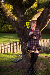 Blonde young woman by the tree holding sunflowers