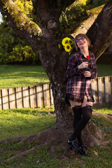 Blonde young woman by the tree holding sunflowers