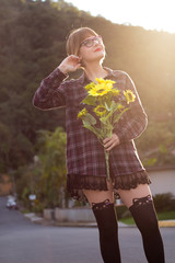 Blodne young woman holding sunflowers by the sunset