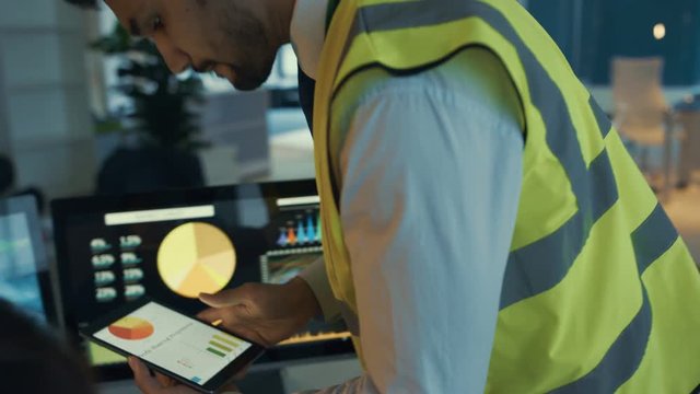  Business team looking at large video screen & computers with charts & data