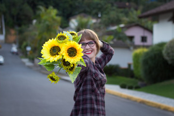 Blonde young woman dancing by the sunset with sunflowers