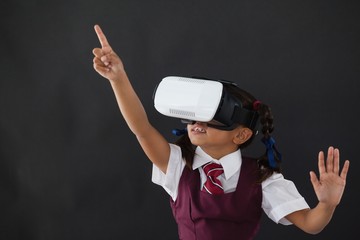 Schoolgirl using virtual reality headset against blackboard